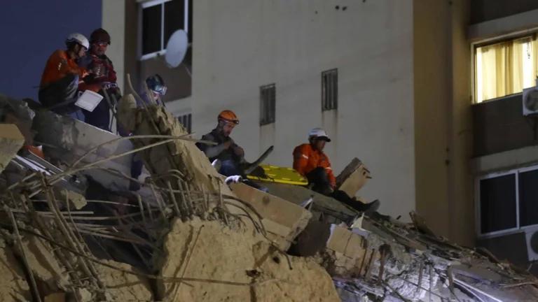 Integrantes de cuerpos de emergencia buscan entre los escombros en la madrugada